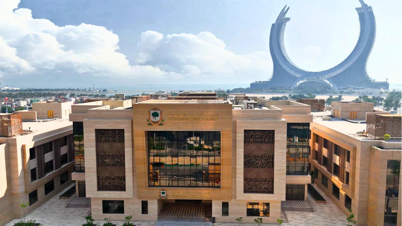 The architectural exterior of the Newton International Academy (NIA) campus in Lusail, Qatar, near the iconic Lusail landmarks.