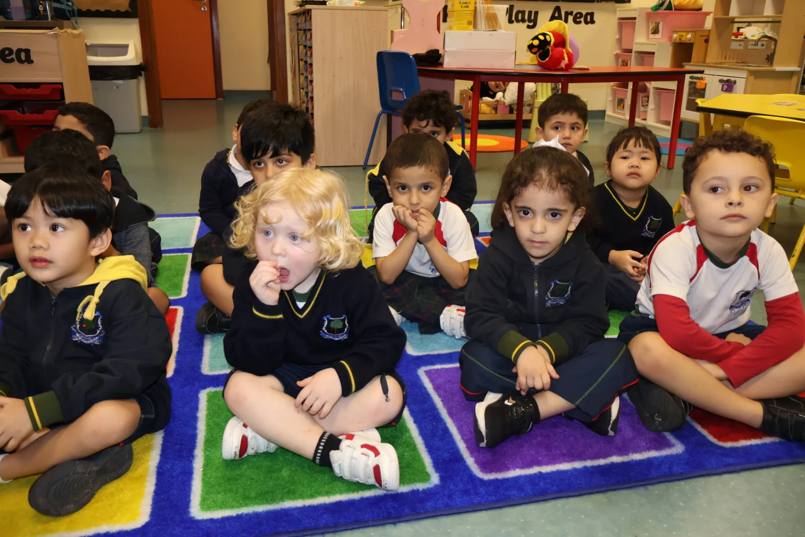 Early Years students sitting together and listening attentively during a teacher-led classroom activity.
